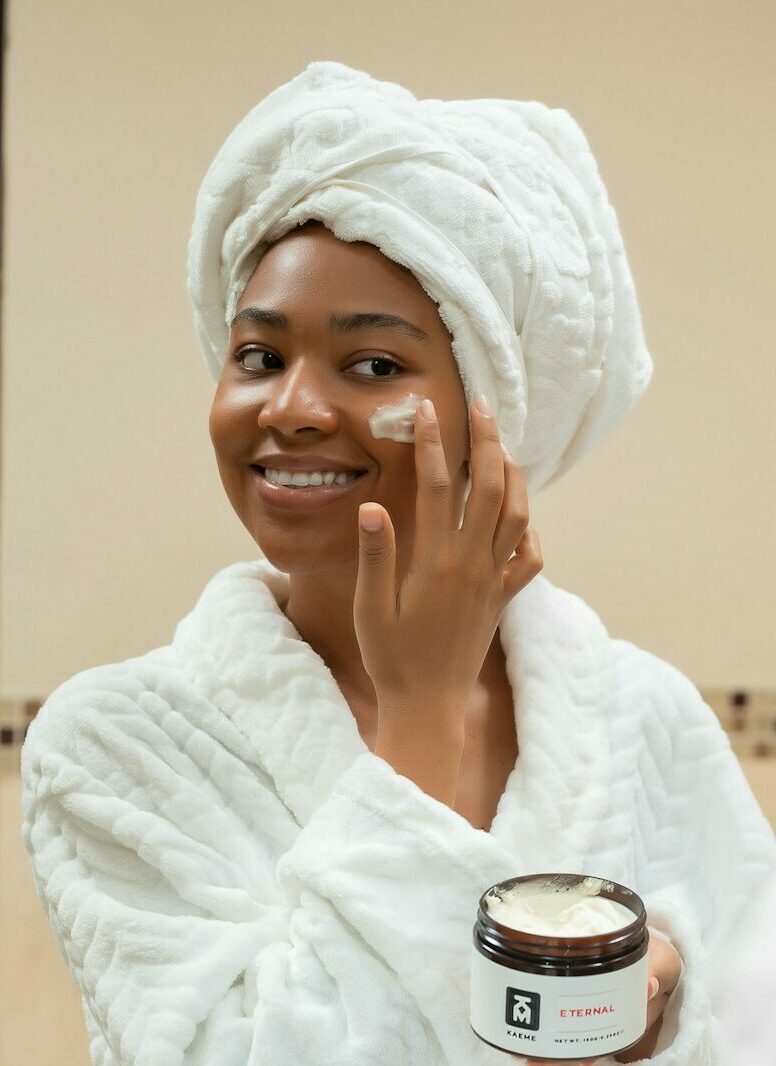 a woman with a towel on her head and a jar of cream on her face